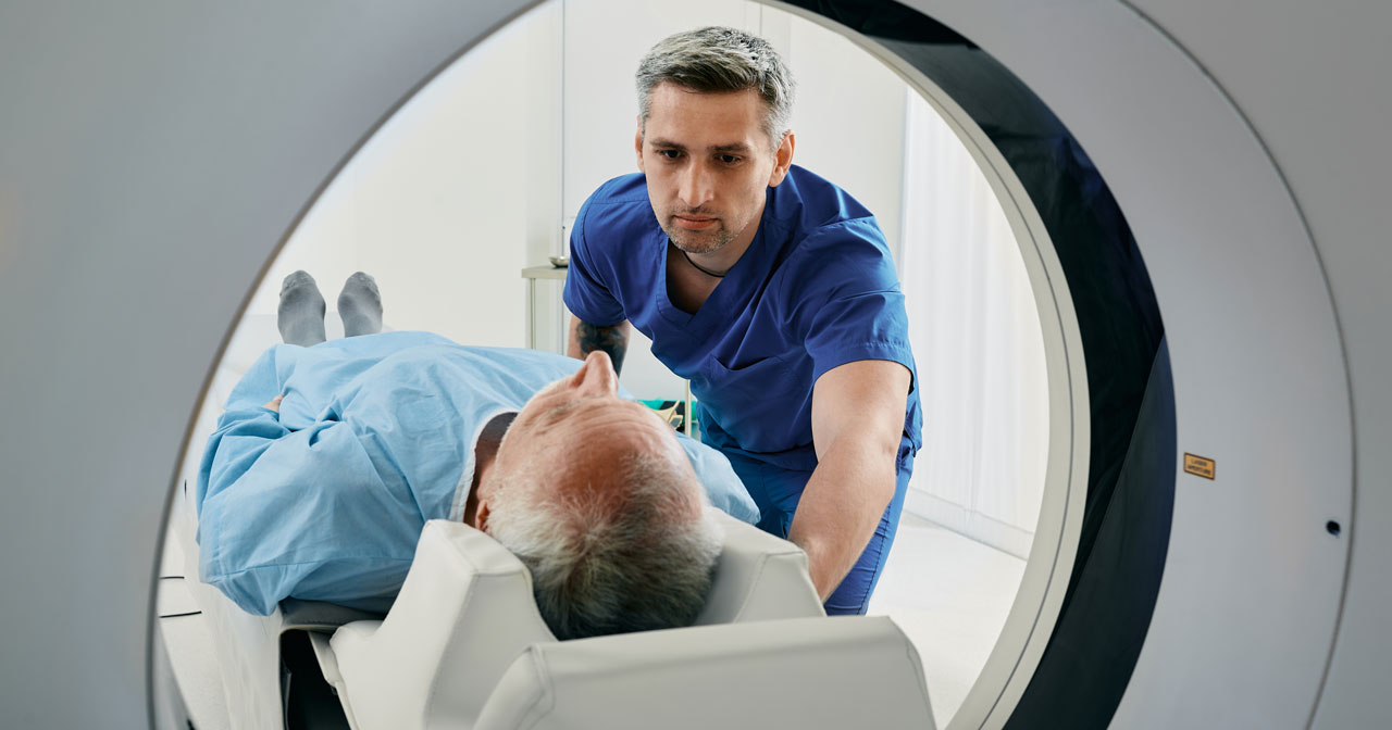 Photo of a healthcare provider speaking with a man in a CT machine