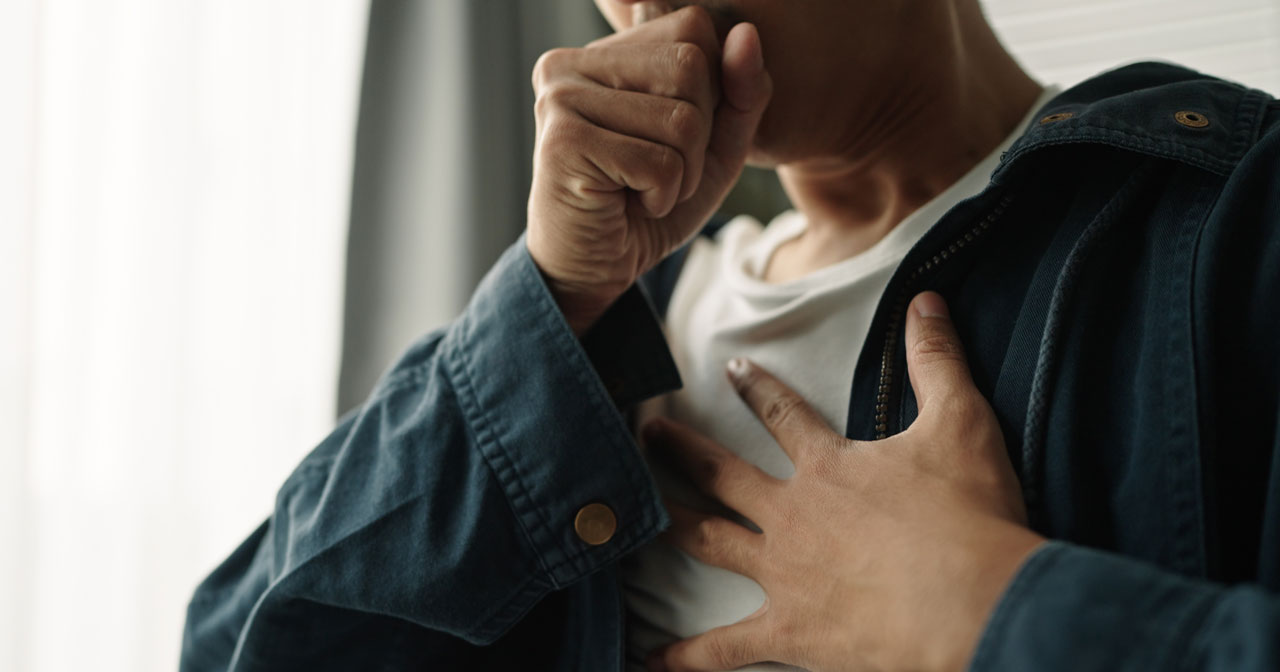 Photo of a man coughing and holding is chest