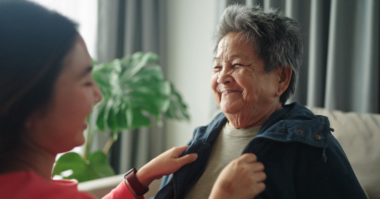 Younger woman helps older woman with clothing